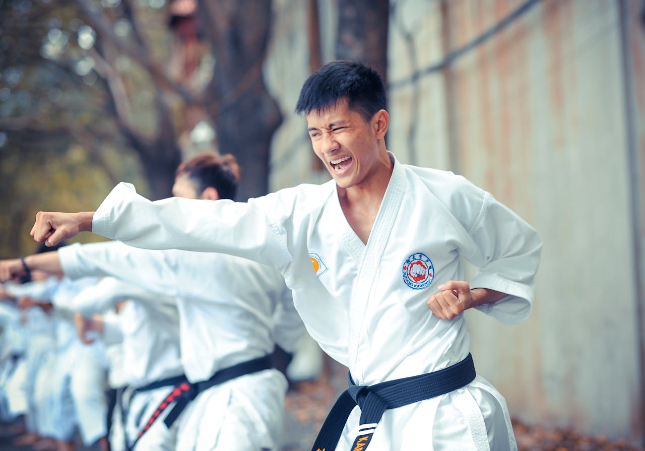 Asian man practices karate outdoors, showcasing skill and determination.